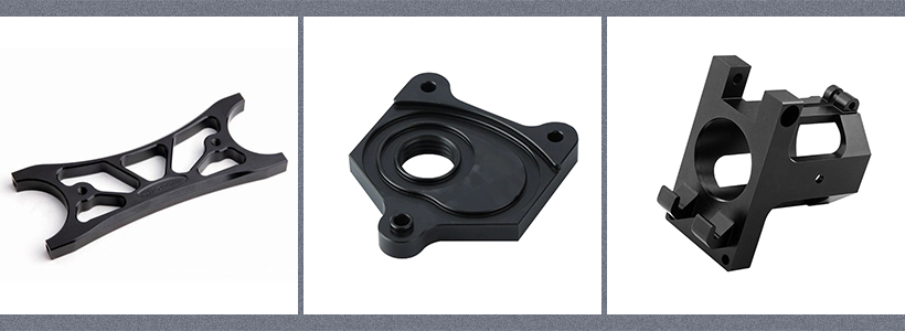 Three black anodized machined plastic parts: a bracket with cutouts, a circular plate with a hole, and a rectangular block with a cutout.